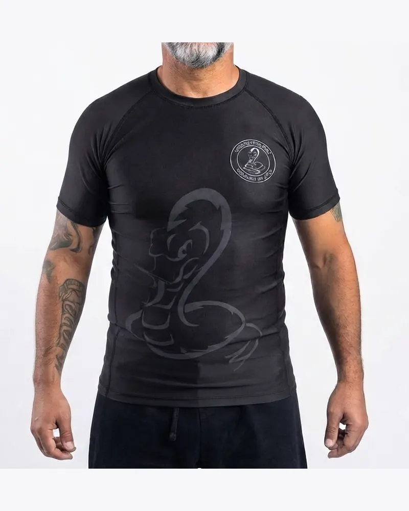 Rashguard negro de manga corta con diseño tono sobre tono de una serpiente, frente