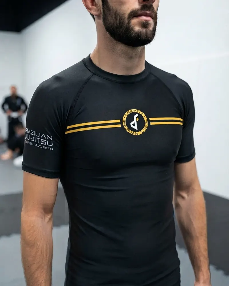 Rashguard negro de manga corta con franjas doradas y el escudo de Favoreto, frente
