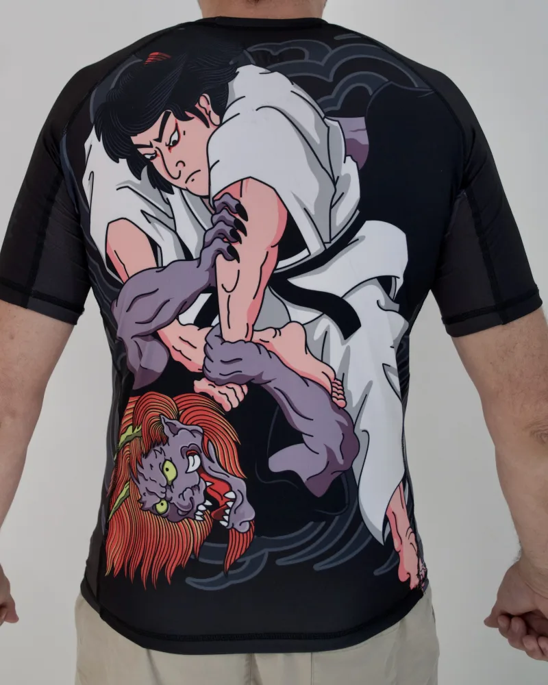 Espalda de un rashguard negro con la ilustración completa de un luchador de jiu jitsu sometiendo a un demonio